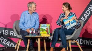 Axel Scheffler und Moderatorin sitzen auf einer Bühne und sprechen. 