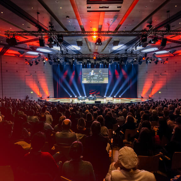 Großer Saal mit Besuchern bei einer Lesung